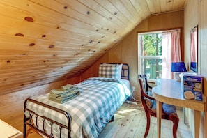 A cozy bedroom with a bed, a chair, a table, and a window.