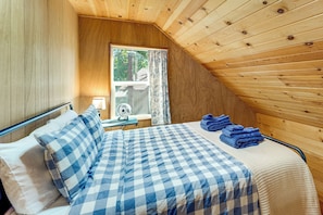 A room with a bed, a window, a fan, and a view of the outdoors.
