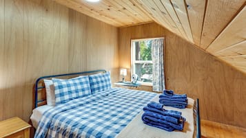 A bedroom with a bed, a nightstand, a window with curtains, and a ceiling fan.