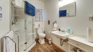 Ein Badezimmer mit Duschkabine, Toilette, Waschbecken inklusive Spiegel und Handtuchhalter.