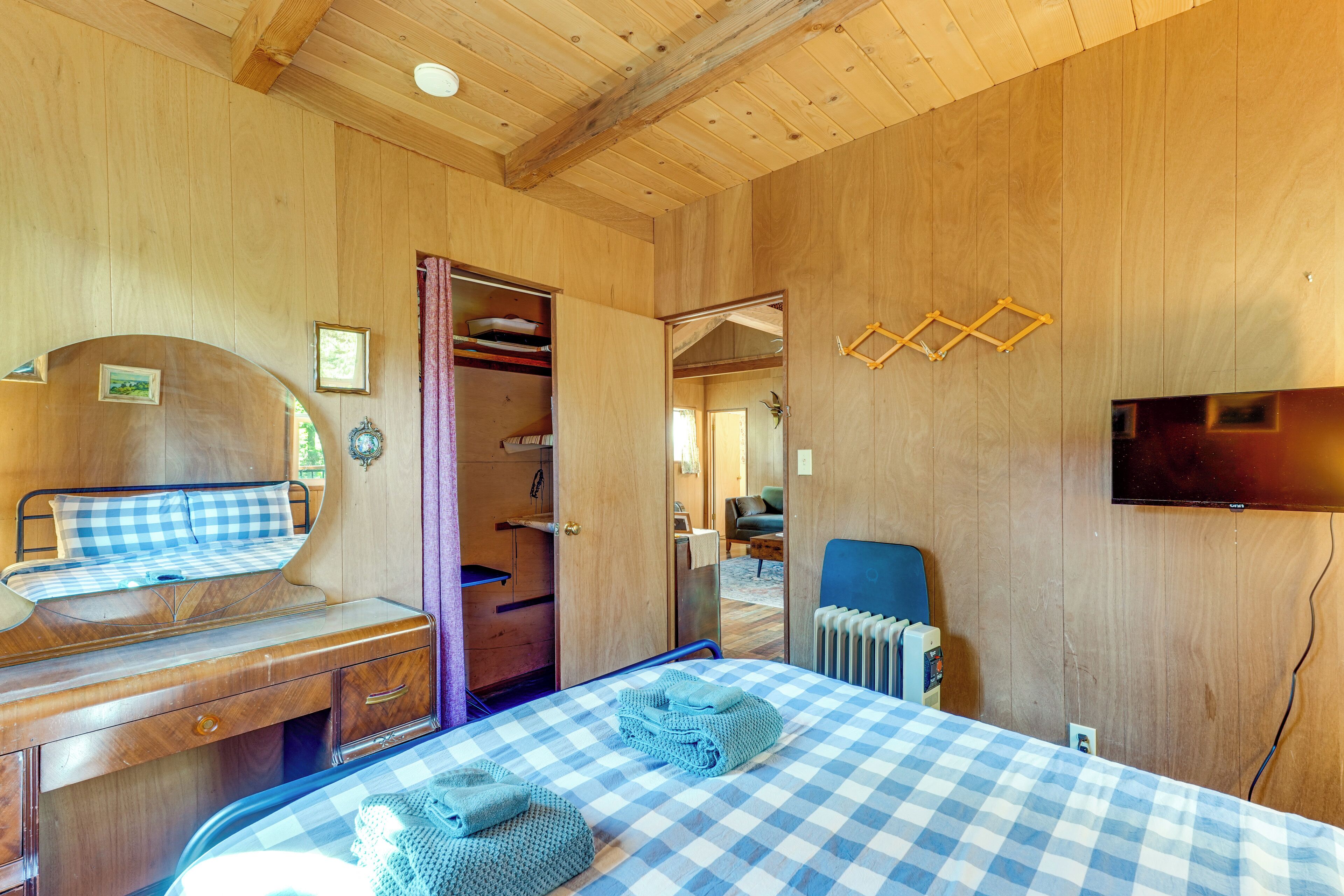 Une pièce en bois avec un lit, un bureau, une chaise, un radiateur et un téléviseur fixé au mur.