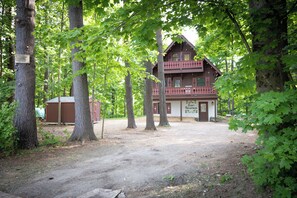 Eine Blockhütte mit zweistöckiger Bauweise, einer Veranda und einer sichtbaren Garage.