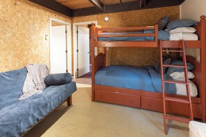 A bunk bed with a ladder, a sofa with cushions, and a door leading to another room. - 'StrautmanHaus' All-Season Berkshire East Chalet (Charlemont)