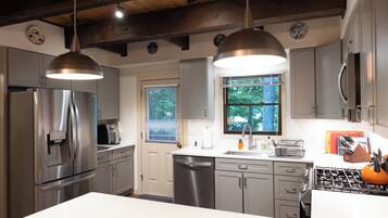 A modern kitchen with stainless steel appliances, pendant lighting, and a large island.