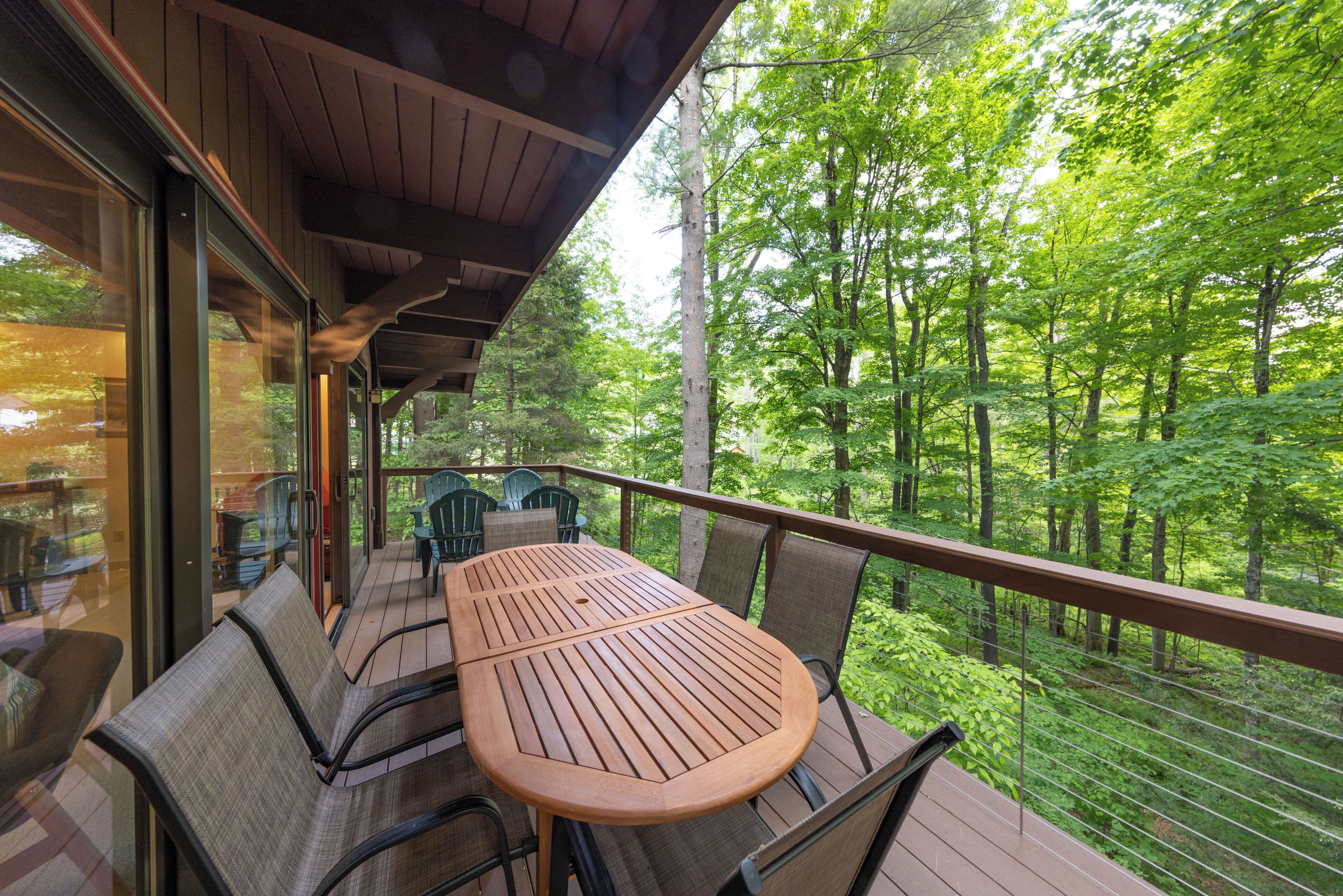 Une terrasse extérieure avec une table et des chaises en bois, donnant sur une zone boisée.