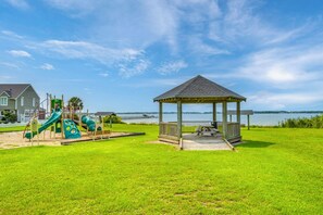 Parque infantil com escorregadores e um coreto com vista para a água.