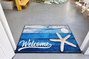 Eine Fußmatte mit einem 'Welcome'-Schild und einem Seestern-Design.