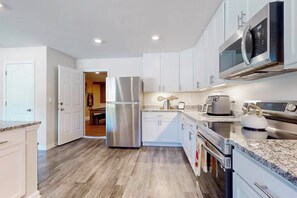 A modern kitchen with stainless steel appliances, white cabinetry, and a wooden floor. - Family Home w/ Game Room, Near Lake Hartwell! (Anderson)