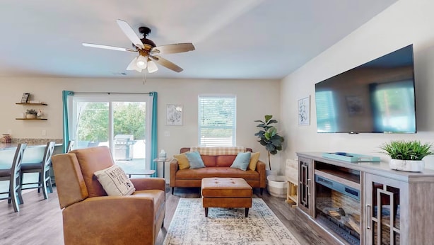 A modern living room with a sofa, ottoman, and a ceiling fan. - Family Home w/ Game Room, Near Lake Hartwell! (Anderson)