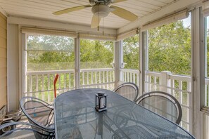 A covered outdoor patio with a table and chairs, large windows, and a ceiling fan. - Golf Days, Pool Vibes! Condo 8 Mi to Sunset Beach (Calabash)
