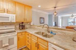 A kitchen with wooden cabinets, a stainless steel sink, a microwave, and a coffee maker. - Golf Days, Pool Vibes! Condo 8 Mi to Sunset Beach (Calabash)