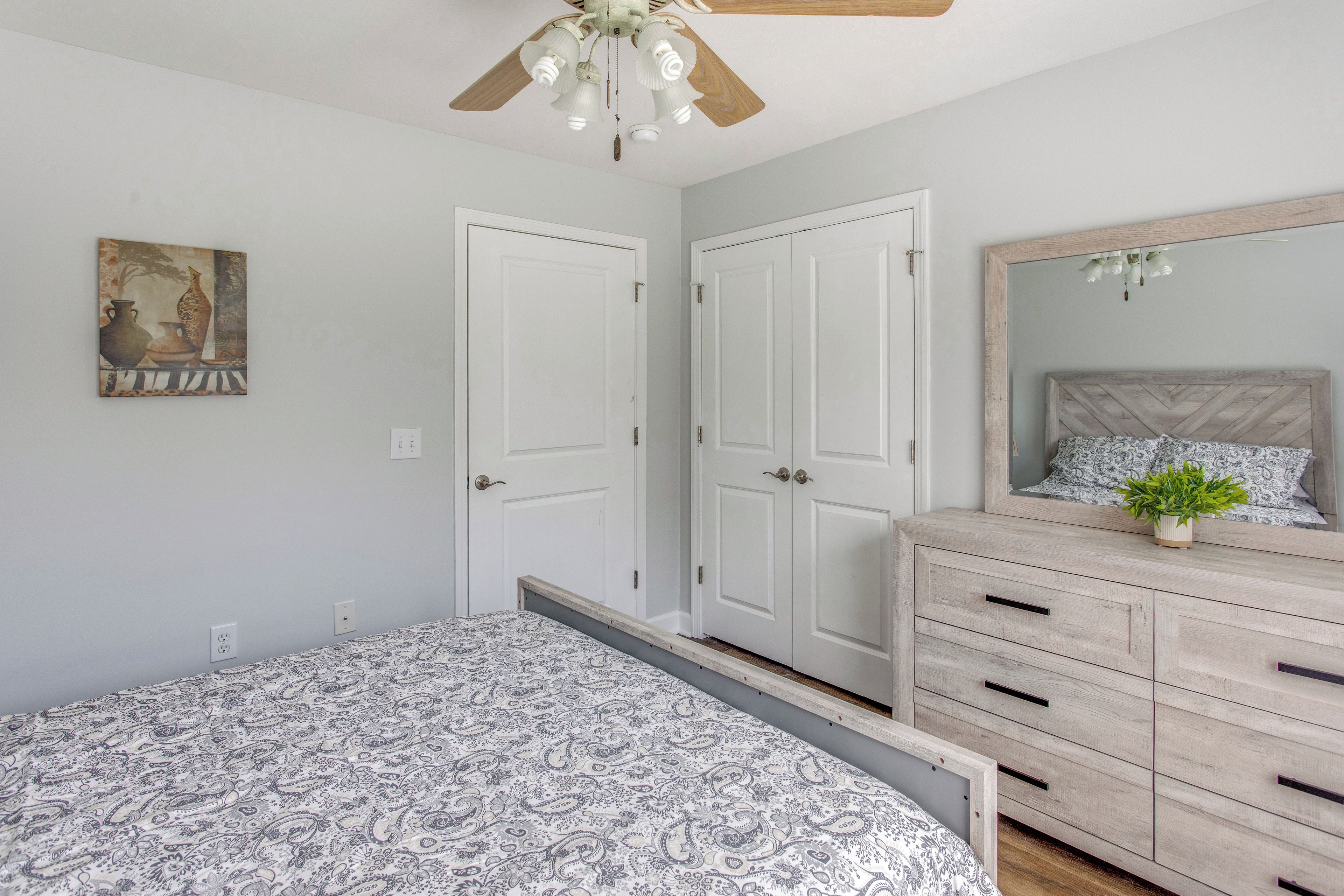 A bedroom with a bed, dresser, and a ceiling fan.