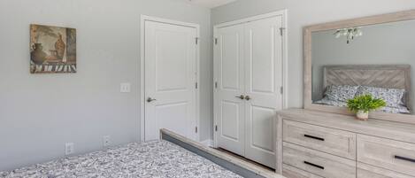 A bedroom with a bed, dresser, and a ceiling fan.