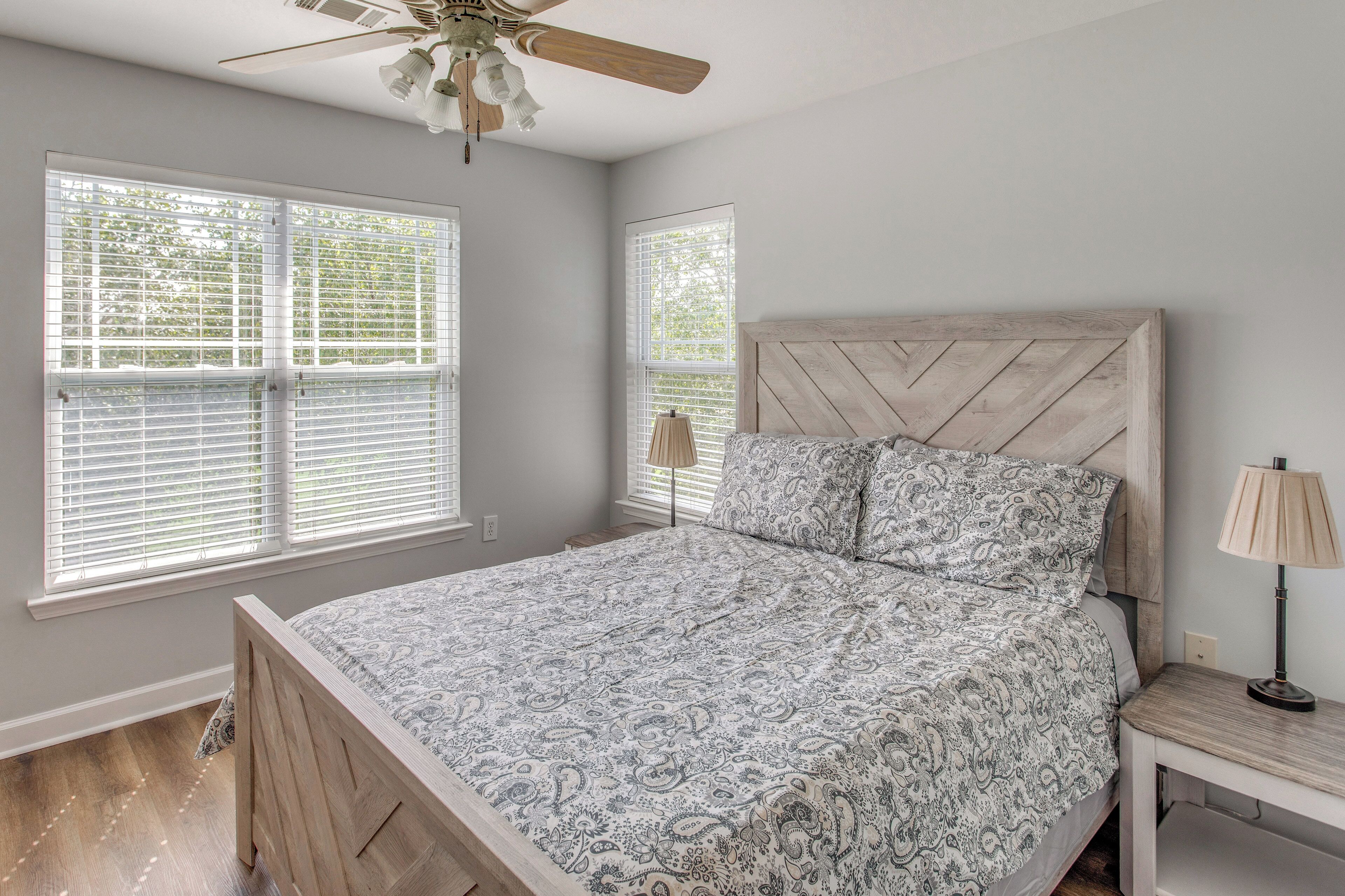 A bedroom with a bed, a nightstand, a lamp, and a ceiling fan.