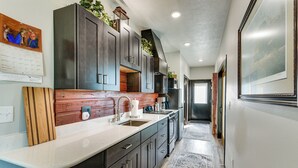 A modern kitchen with dark cabinetry, a white countertop, and a built-in stove.