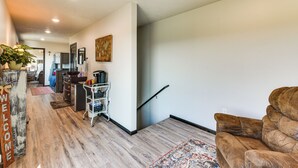 A spacious living area with a sofa, a coffee table, and a rug. There is a kitchen area with cabinets and a countertop visible in the background.