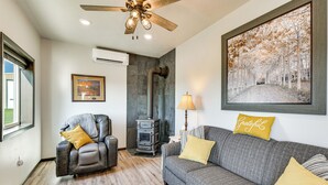A living room with a fireplace, a ceiling fan, a sofa, a chair, and a framed picture on the wall.