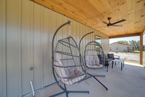 A covered patio area with two hanging chairs and a ceiling fan. - Gateway to State Park & Lake! Inviting Vian Cabin (Vian)