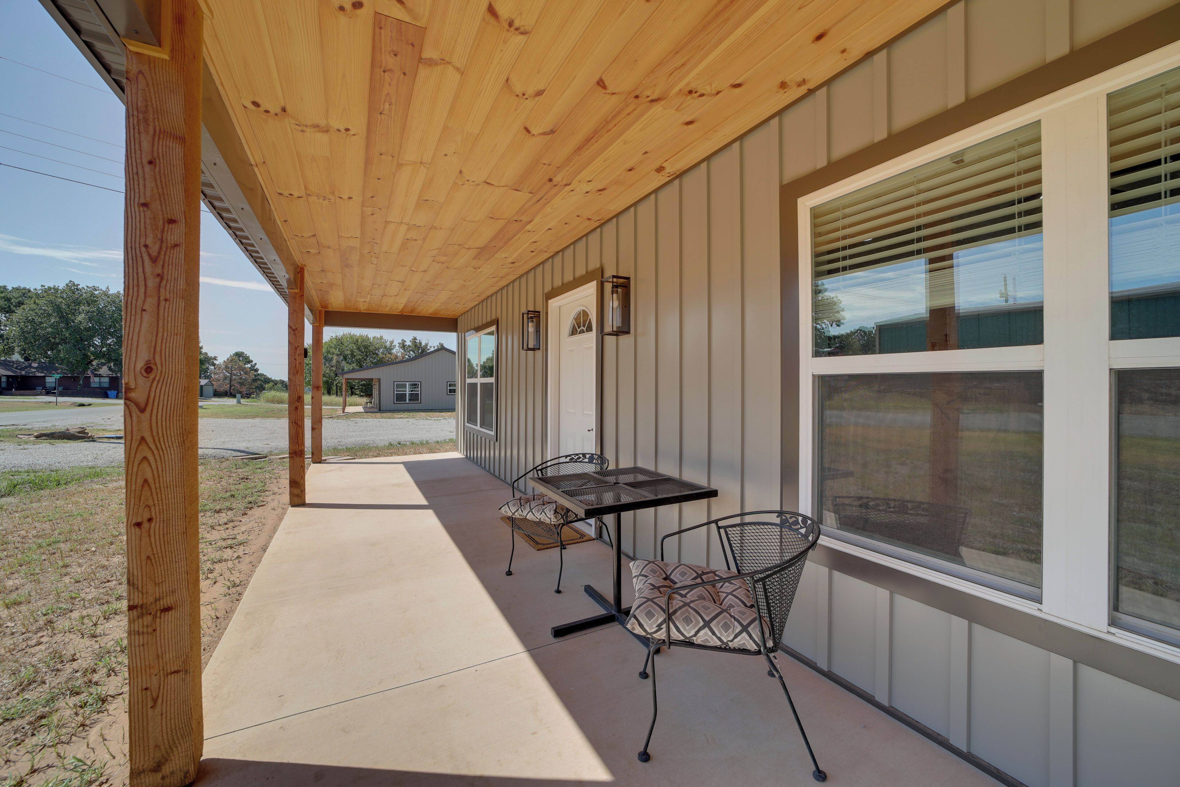 Un área de patio techada con una mesa, sillas, una puerta y una ventana con persianas.