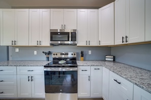 A modern kitchen with white cabinets, a stainless steel microwave, and a built-in oven. - Gateway to State Park & Lake! Inviting Vian Cabin (Vian)