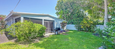 A residential property with a covered outdoor area, a lawn, and various plants.