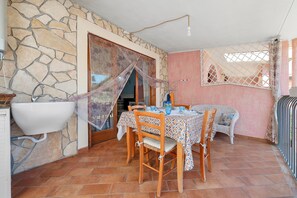A dining area with a stone wall, a sink, and a table set for two. - Holiday Home 'Tanit' with Private Terrace, Wi-Fi and Air Conditioning (Villasimius)