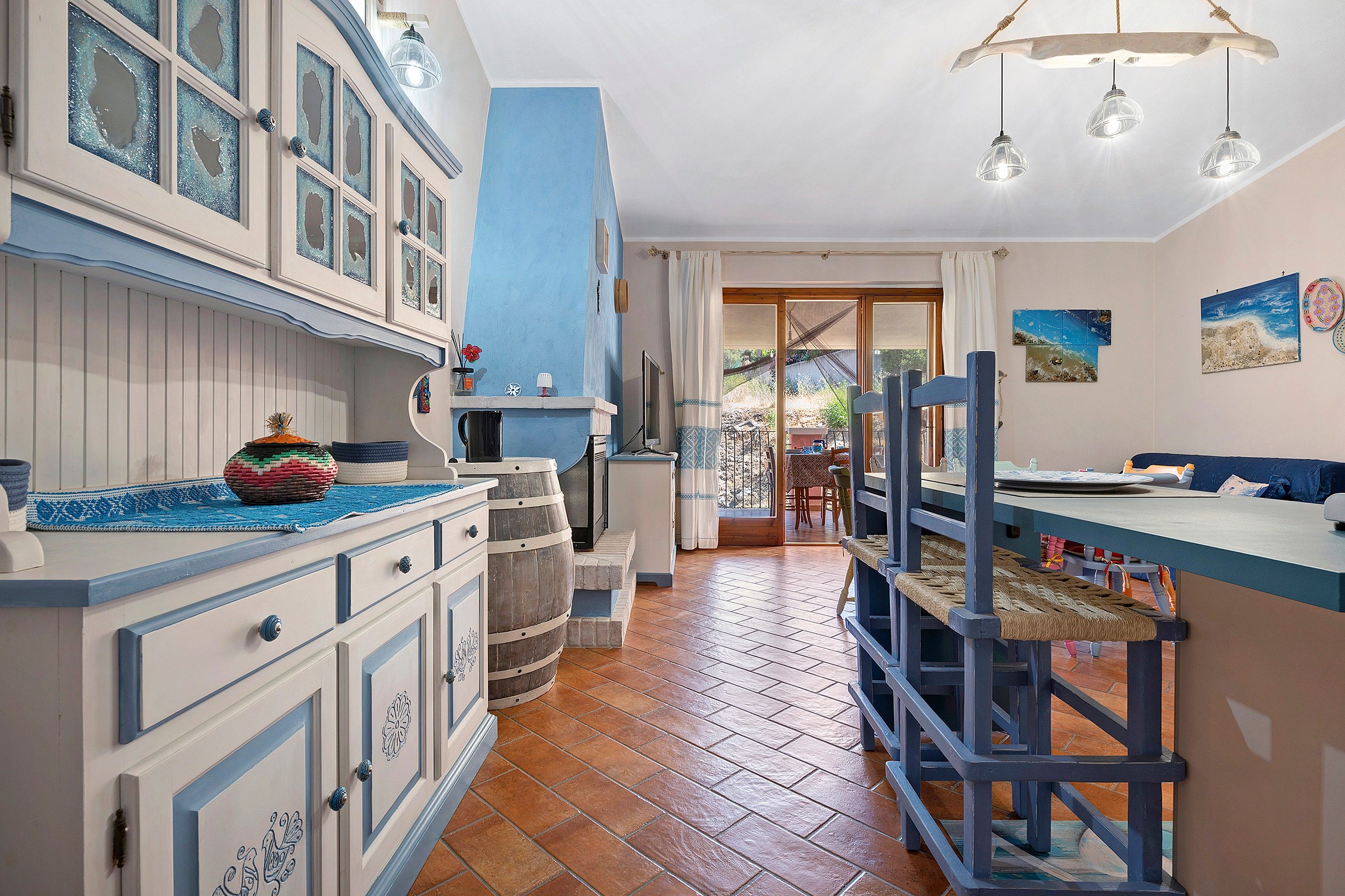 A kitchen with a blue and white color scheme, wooden barrels, and a view to the outside.