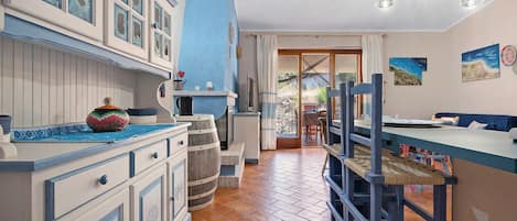 A kitchen with a blue and white color scheme, wooden barrels, and a view to the outside.