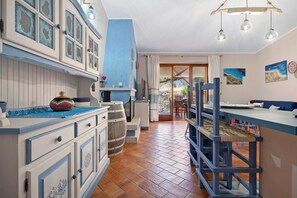A kitchen with a blue and white color scheme, wooden barrels, and a view to the outside. - Holiday Home 'Tanit' with Private Terrace, Wi-Fi and Air Conditioning (Villasimius)
