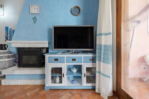 Un salon avec une cheminée, un téléviseur et un meuble avec des tiroirs.