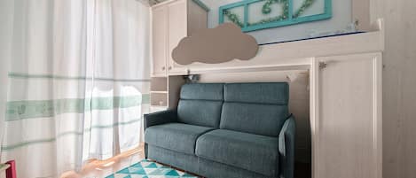 Ein Zimmer mit einem Bett, einem Vorhangfenster, einer Wandablage und einem gemusterten Teppich.
