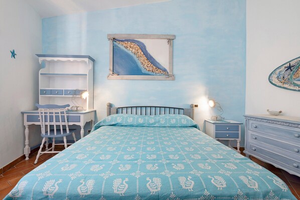 Une chambre à coucher comprenant un lit, un bureau, une chaise, une commode et une étagère fixée au mur.