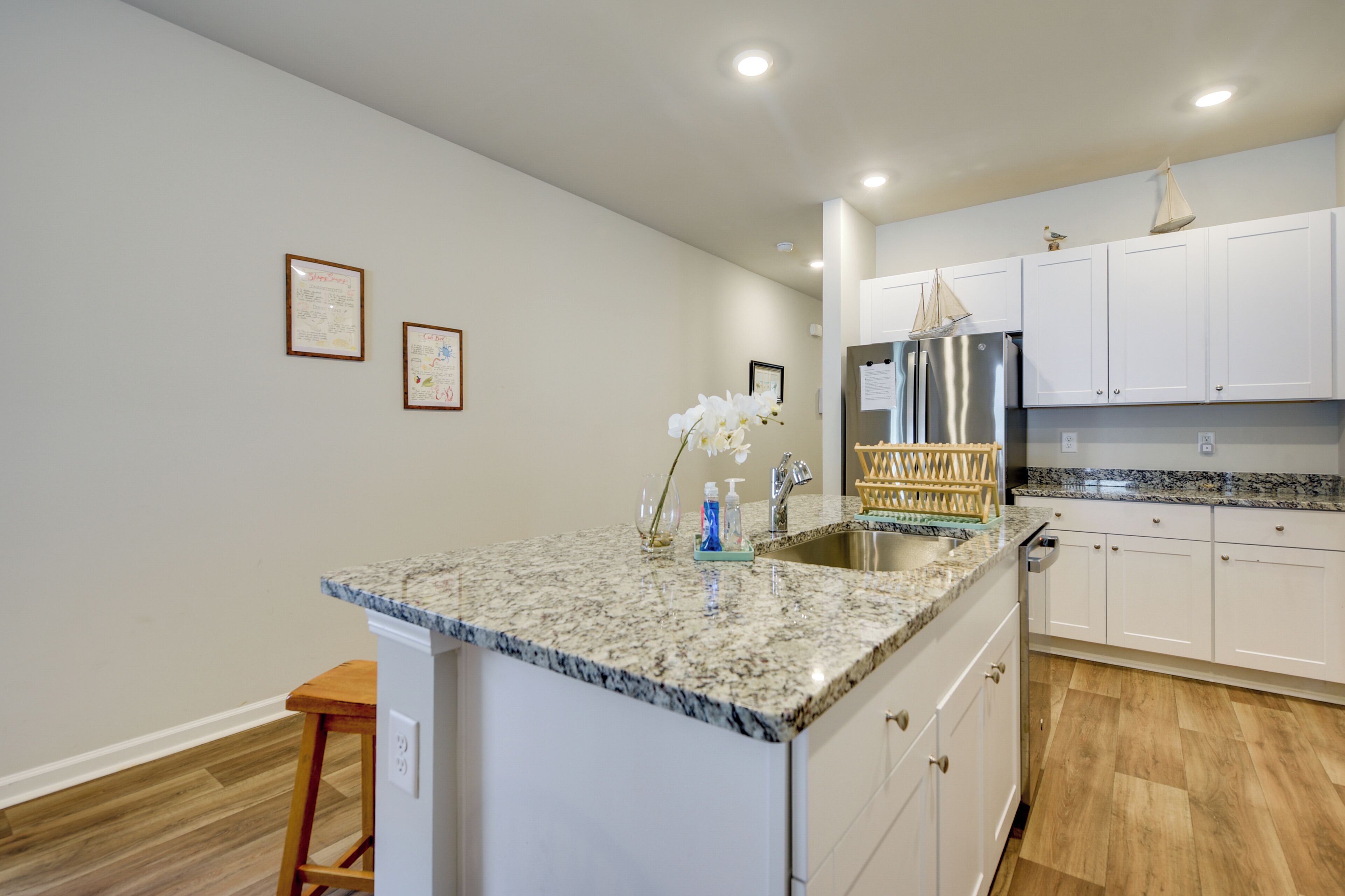 A kitchen with white cabinets, a granite countertop, and a stainless steel refrigerator.