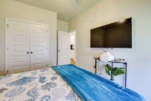 A bedroom with a bed, a TV mounted on the wall, and a hallway leading to another room. - Hammock, Grill & Patio! Sunfish Cove Home (Sunset Beach)