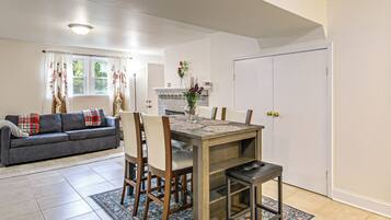 Un salon avec un canapé, une table à manger et des chaises, une cheminée et une porte.