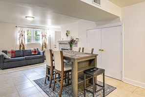 Ein Wohnzimmer mit einer Couch, einem Esstisch mit Stühlen, einem Kamin und einer Tür.