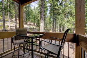 Eine Holzterrasse mit Tisch und Stühlen, mit Blick auf ein bewaldetes Gebiet.