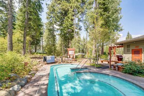 Ein Pool, umgeben von Bäumen, mit einer überdachten Terrasse und Grillplatz.