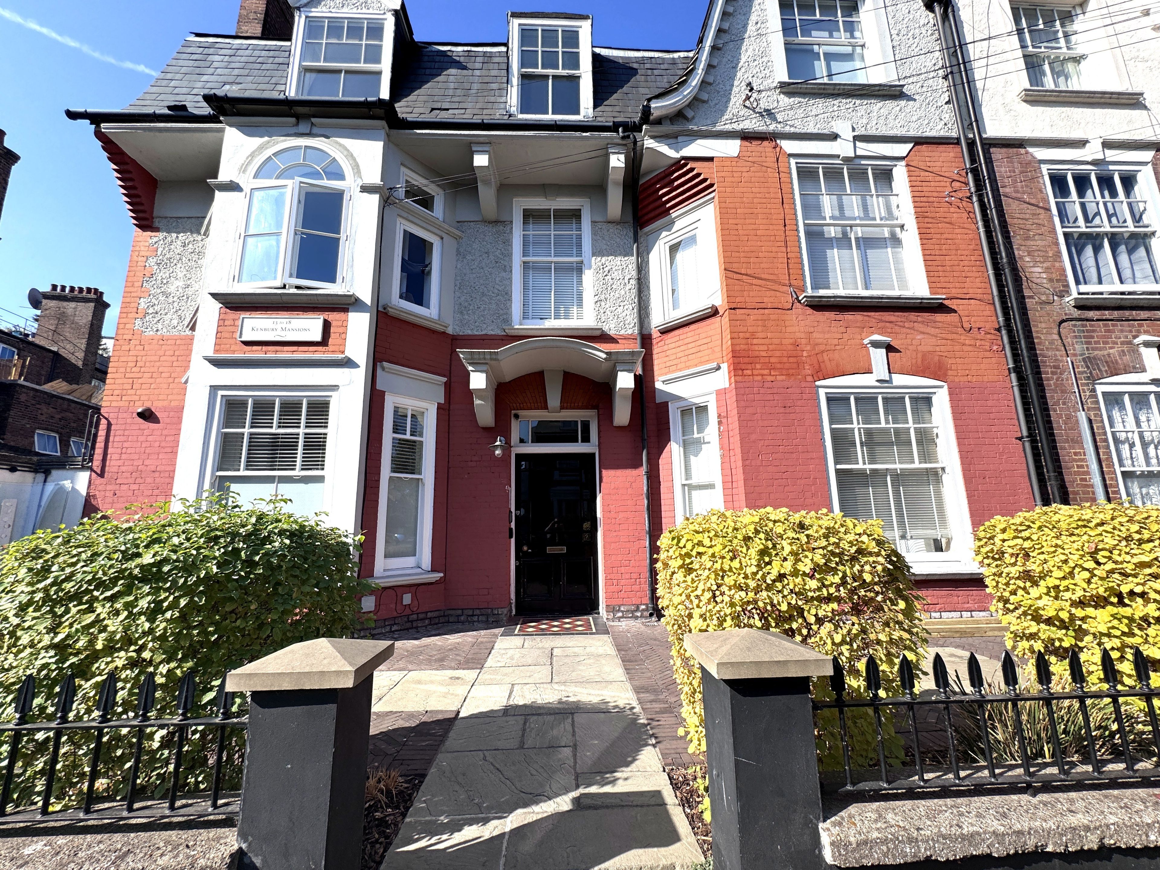 A two-story house with a red brick facade, white trim, and multiple windows.