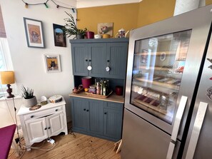 Una cuina amb un armari blau, un frigorífic d'acer inoxidable i diferents objectes de cuina damunt el taulell.