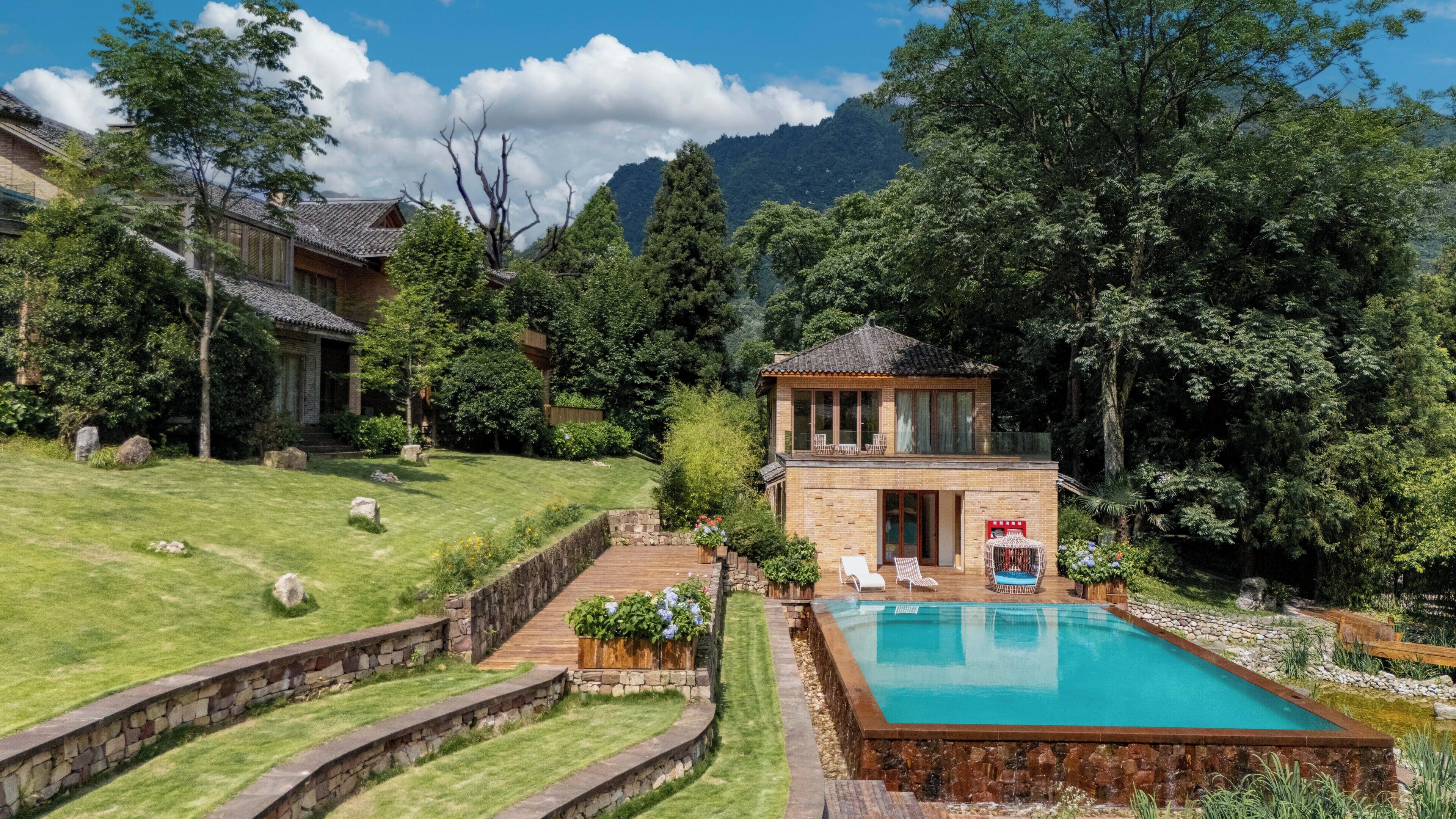 Une propriété résidentielle dotée d’une piscine, d’une terrasse en bois et offrant une vue sur une chaîne de montagnes.