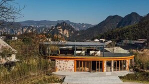 A modern building with a curved glass facade, surrounded by a mountainous landscape.