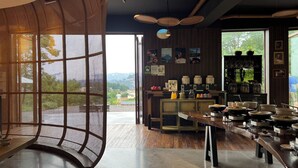 Un ristorante con vista sulle montagne, un'area bar con diversi tipi di bottiglie e un angolo buffet.