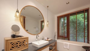 Un bagno moderno con uno specchio grande, un lavandino, una vasca e una finestra con persiane.