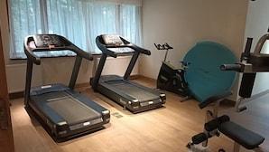 A room with two treadmills, a stationary bike, and a bench.