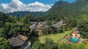 A resort with multiple buildings surrounded by lush greenery and mountains.
