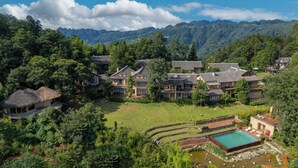Un resort dall'architettura tradizionale, con piscina e montagne sullo sfondo.