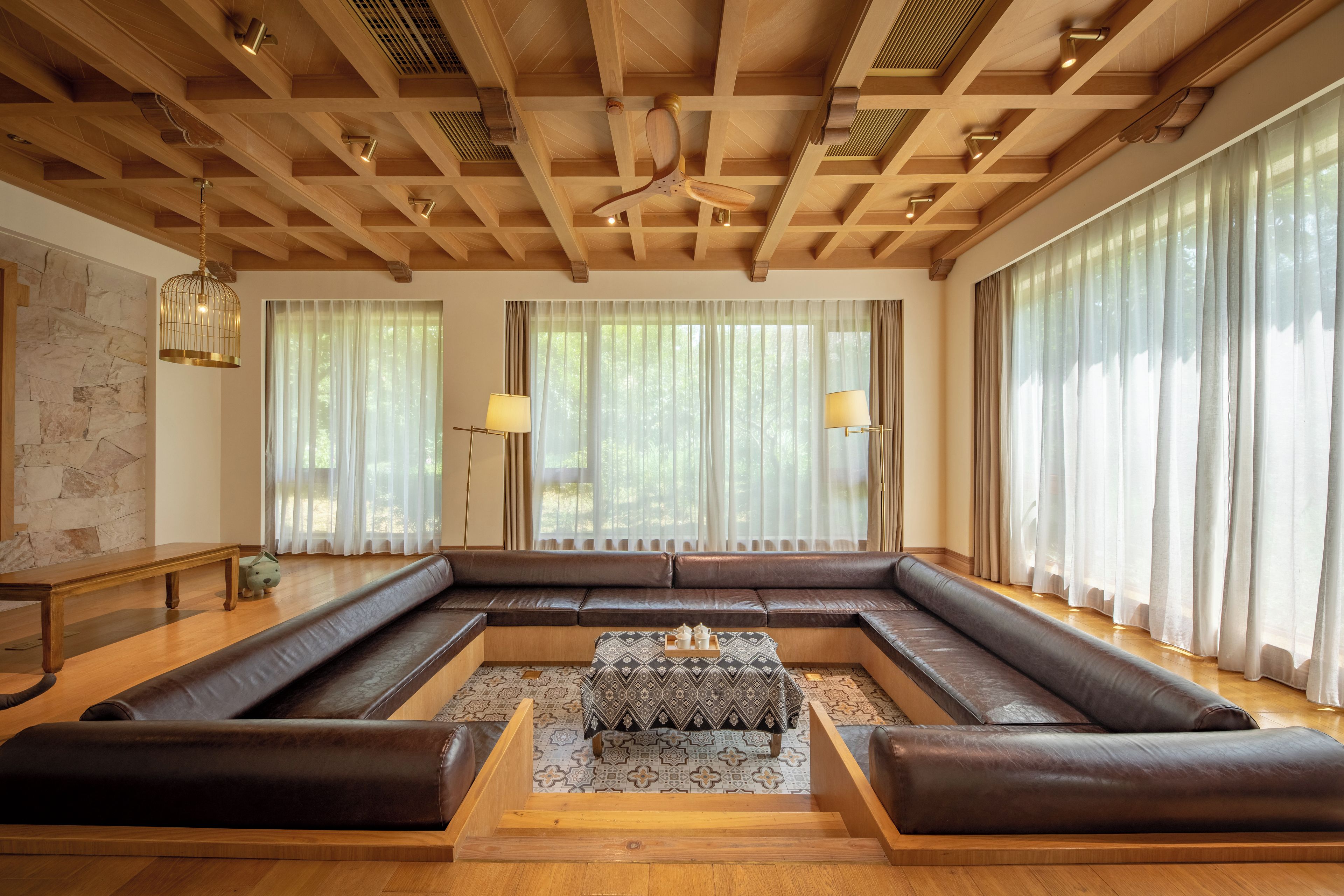 Amplia sala de estar con un sofá en forma de L, una mesa de centro y un techo de madera con vigas a la vista.