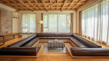 Amplia sala de estar con un sofá en forma de L, una mesa de centro y un techo de madera con vigas a la vista.