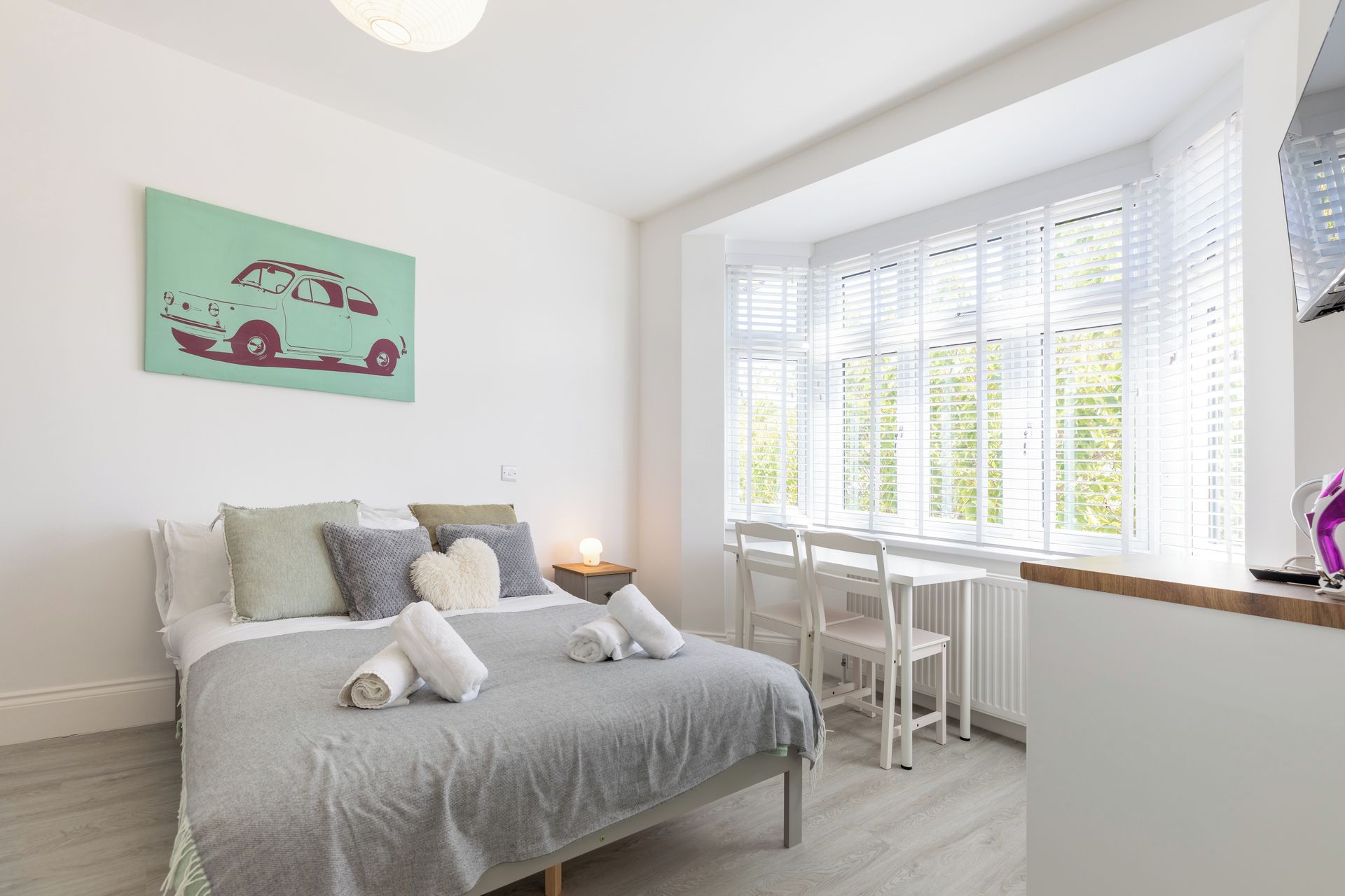 Un dormitorio con cama, escritorio y ventana con persianas.
